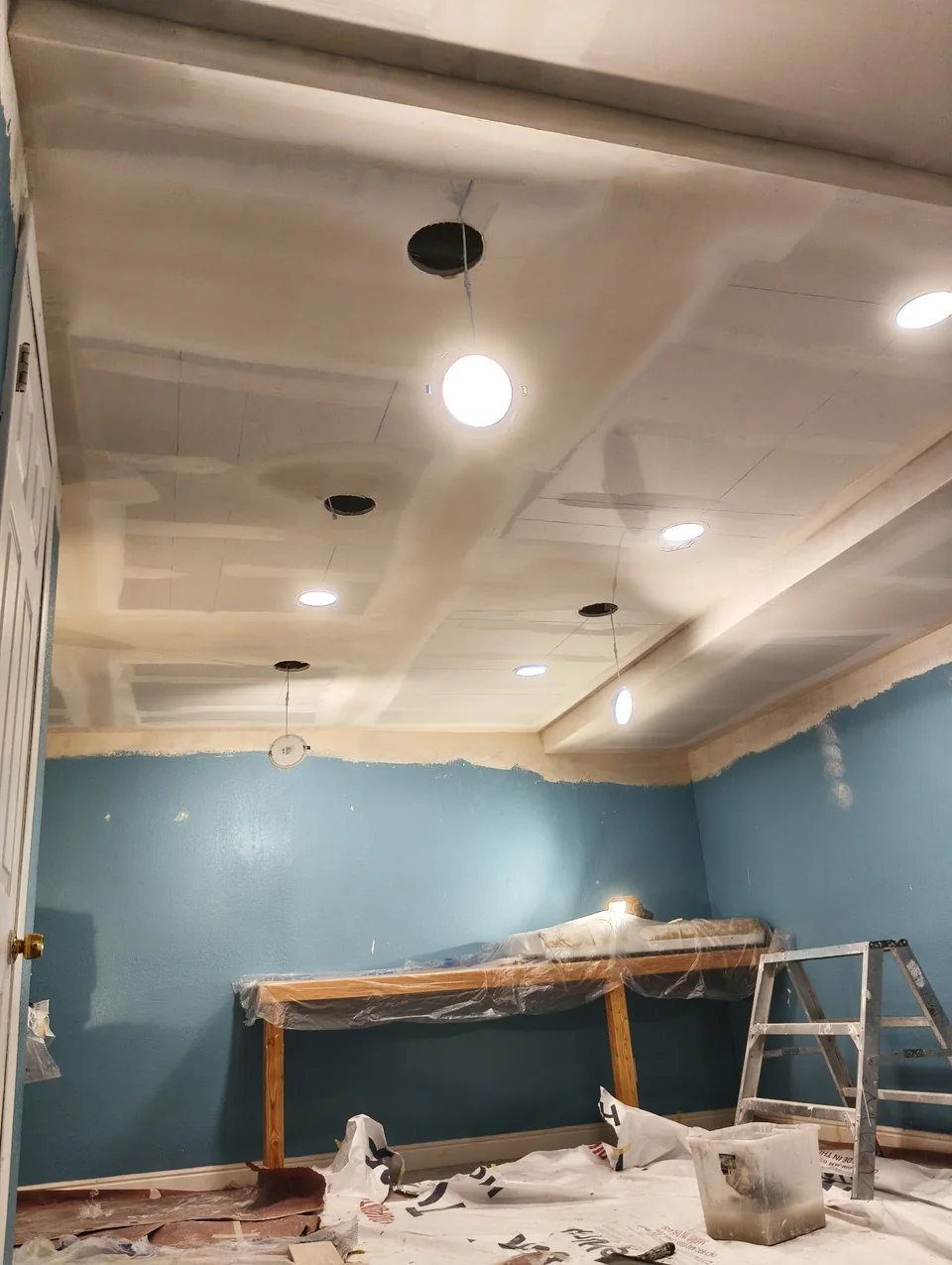 Ceiling with taped drywall joints and light openings above blue walls