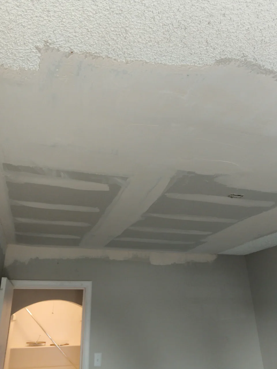 Patched drywall area with taped joints in a textured ceiling