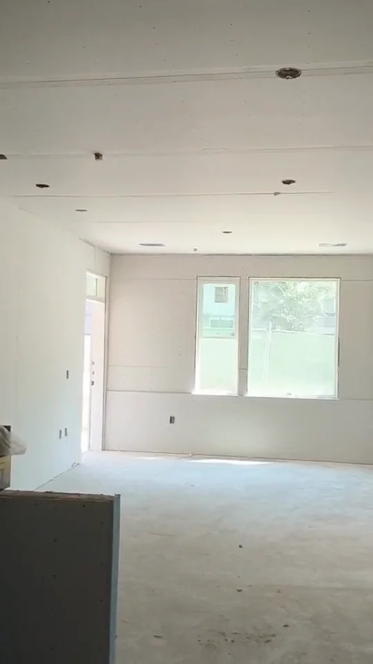 Drywall-lined room with a bright window at the far end